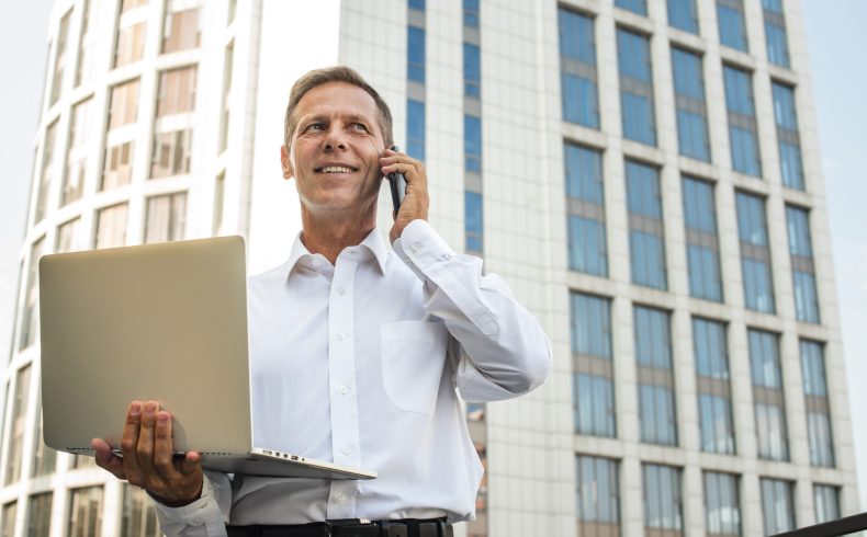 businessman-holding-laptop-talking-phone